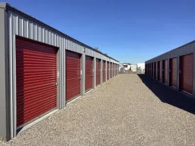Row of storage units with red roll-up doors on a clear day